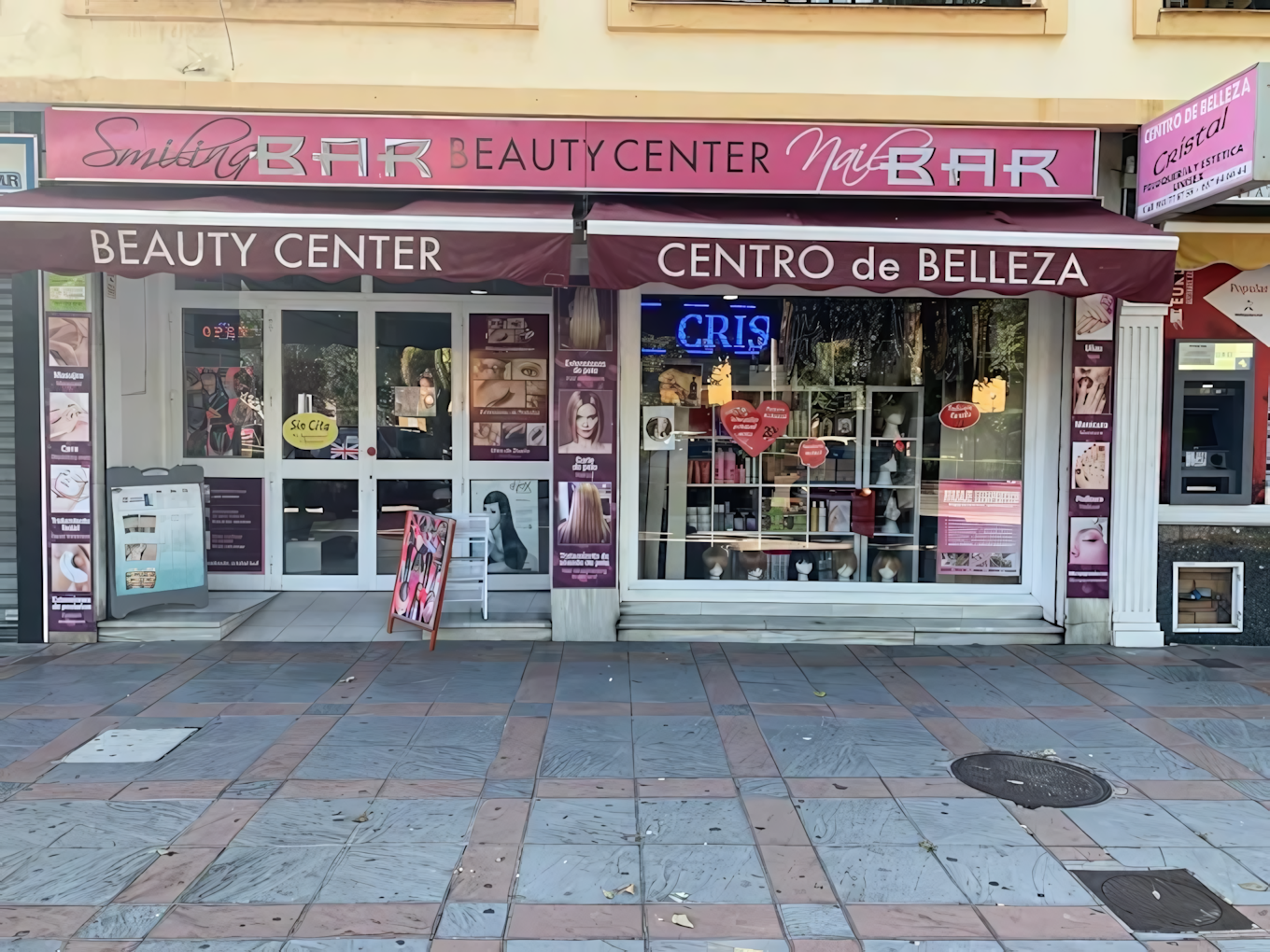 Fachada de un centro de belleza llamado "Smiling Bar Beauty Center Nail Bar", con vitrinas decoradas con imágenes promocionales y un letrero en español que dice "Centro de